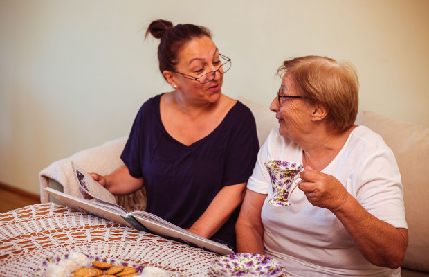 Trabajadora de asistencia a domicilio comparte una merienda con una señora mayor mientras mantienen una conversación animada